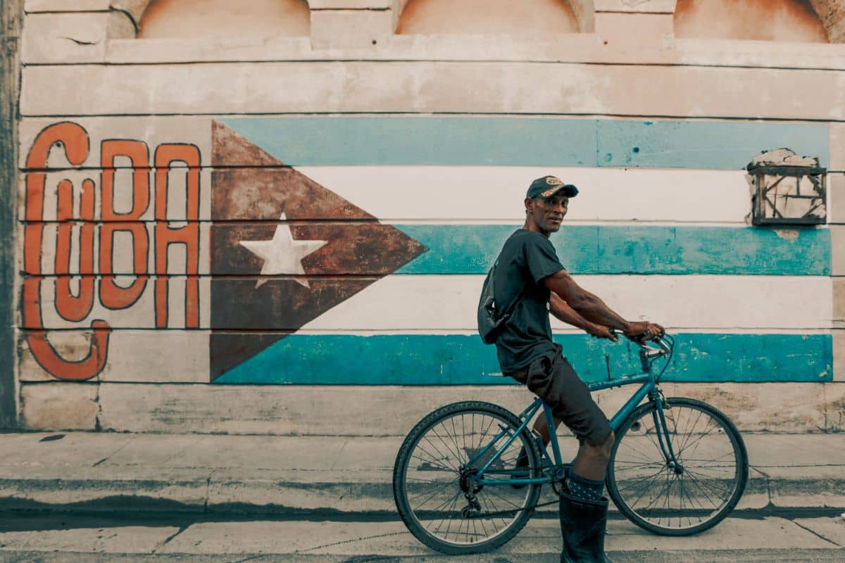 Painted Cuban flag on the wall with a man on his bike standing in front