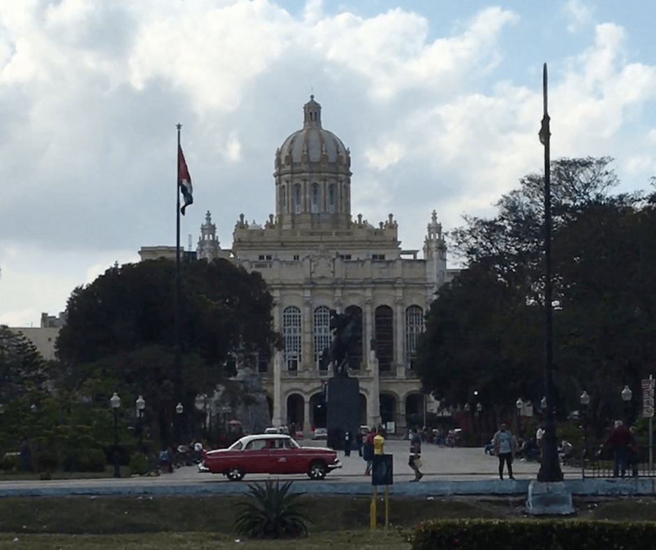 Museo de la Revolución Museum in the background with a vintage car passing in front