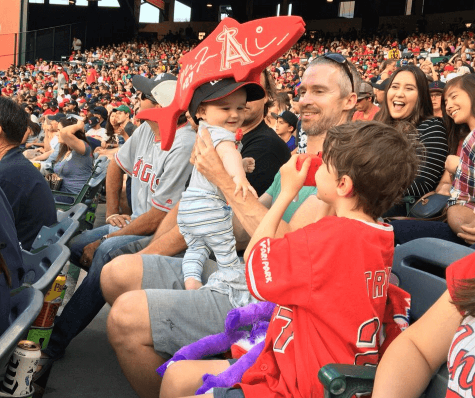 Lukas wearing a Mike Trout fish hat, as the crowd around laugh
