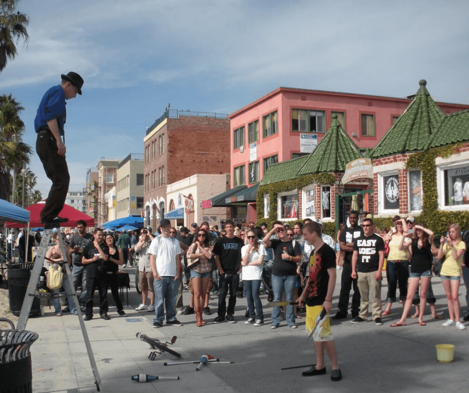 A street performer performing in front of a crowd that has gathered on the boardwalk