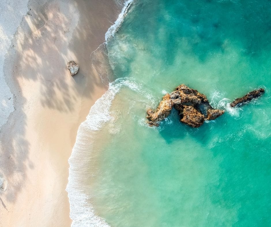 Stunning wide angle aerial drone view of a rock in the water at Otama Beach