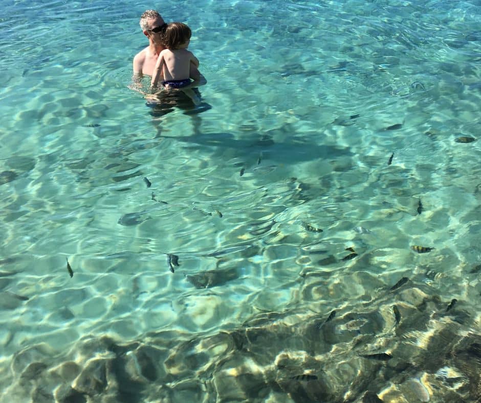 Dad with Sawyer in the waters of Caleta Buena. The fish swimming around them