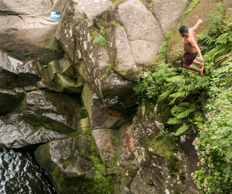 A man jumping from from one of the rocks into the river below