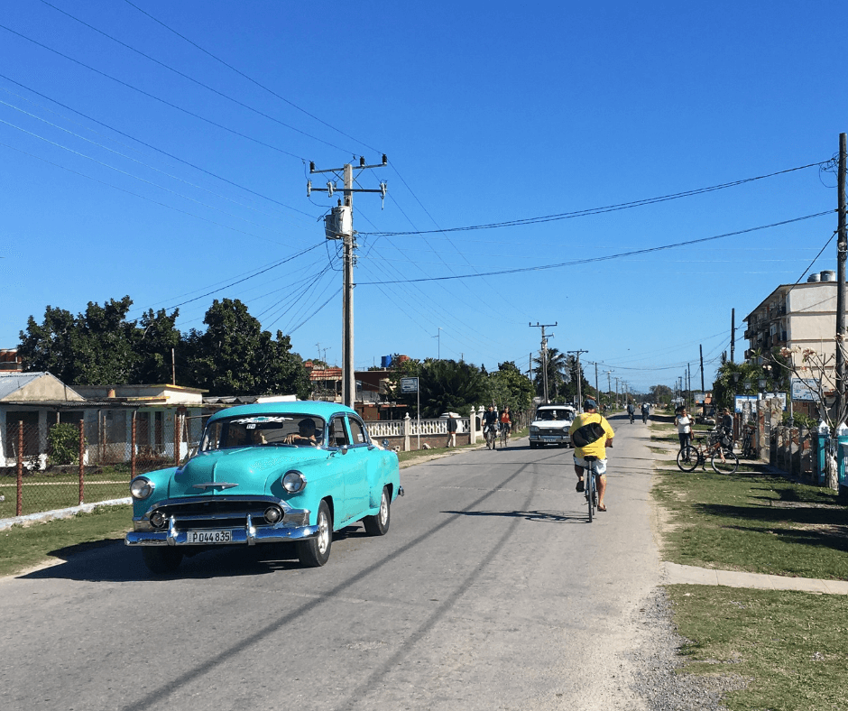 Main street in Playa Girōn, with a bike and a vintage car sharing the road. Playa Girōn a spot not to be missed.