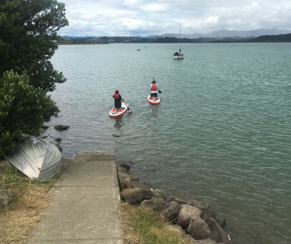 Two paddle boarders setting out on the harbour, certainly one of the most relaxing things to do in Ohope Beach